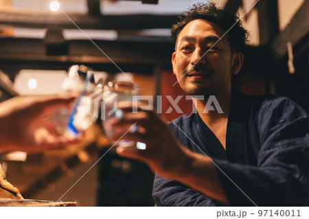 囲炉裏でお酒を飲む髭の男性 97140011