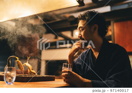 囲炉裏でお酒を飲む髭の男性 97140017