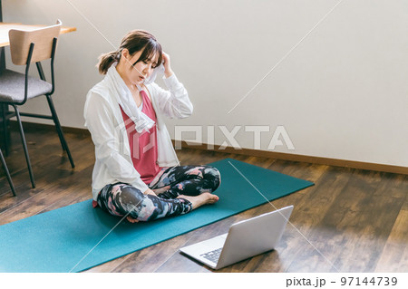 家のリビングでノートパソコンを使いながらヨガをするアジア人女性(困る・悩む) 家のリビングでノートパソコンを使いながらヨガをするアジア人女性(困る・悩む) 97144739