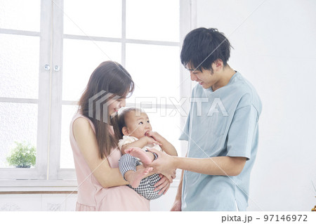 家で赤ちゃんと遊ぶ両親のポートレート 97146972