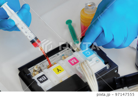 Printer maintenance. Master fills inkjet printer with ink or syringe paint. Hands with gloves close 97147555