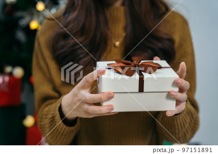 Merry Christmas, Hands opening christmas gift on background of christmas tree with lights. in festive room close up. Merry Christmas, Hands opening christmas gift on background of christmas tree with lights. in festive room close up. 97151891