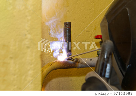 Professional welder welding with electric old metal pipes for heating. Old heating system renovation concept 97153995