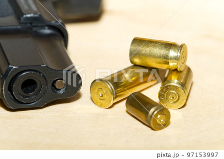 shell casings and barrel of a pistol close-up on a wooden table in a shooting range or at a crime scene. crime concept 97153997