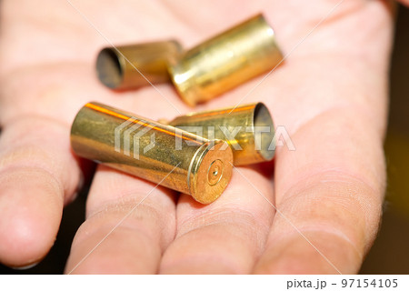 close-up of bronze cartridge cases on a hand in a shooting range or at a crime scene. crime concept close-up of bronze cartridge cases on a hand in a shooting range or at a crime scene. crime concept 97154105