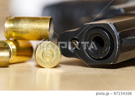shell casings and barrel of a pistol close-up on a wooden table in a shooting range or at a crime scene. crime concept shell casings and barrel of a pistol close-up on a wooden table in a shooting range or at a crime scene. crime concept 97154106