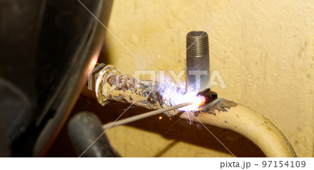 Professional welder welding with electric old metal pipes for heating. Old heating system renovation concept 97154109
