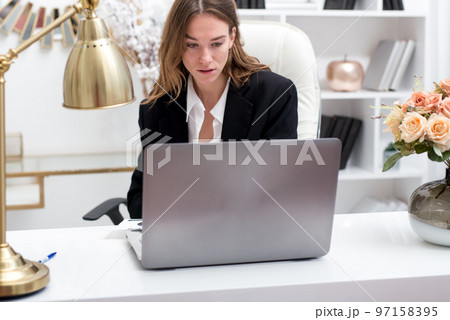 Young woman working with a laptop at her desk in the office Young woman working with a laptop at her desk in the office 97158395