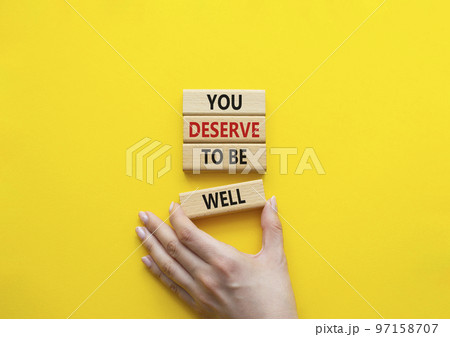 You deserve to be well symbol. Wooden blocks with words You deserve to be well. Beautiful yellow background. Businessman hand. You deserve to be well concept. Copy space. 97158707