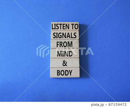 Body and mind wellness symbol. Concept words Listen to signals from mind and body on wooden blocks. Beautiful blue background. Medical and mental or physical health concept. Copy space. 97159472
