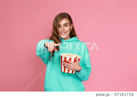woman in sweatshirt watching movie film, eating popcorn woman in sweatshirt watching movie film, eating popcorn 97161739