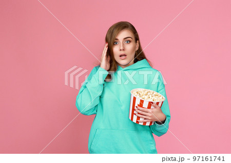 amazed brunette woman holding bucket of popcorn 97161741