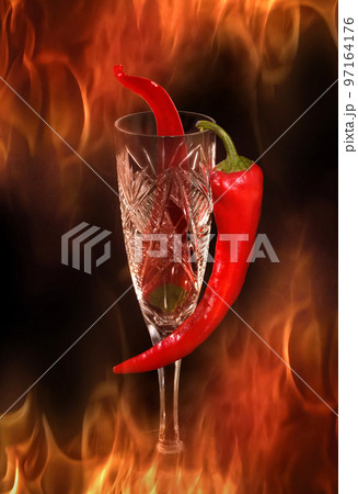 Beautiful red chili pepper in a glass, on fire, on a black background Beautiful red chili pepper in a glass, on fire, on a black background 97164176