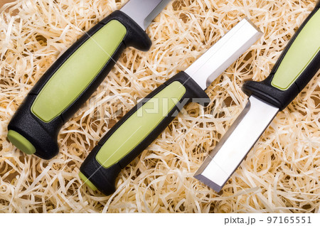 Woodworking tool. Carpentry tool. Sharp chisel and wood shavings. Wood cutting tool. Knife chisel in three angles. 97165551