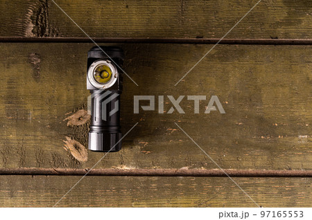 Small flashlight. Lantern lying on a green military box. Curved lantern. View from above. Space for text. 97165553