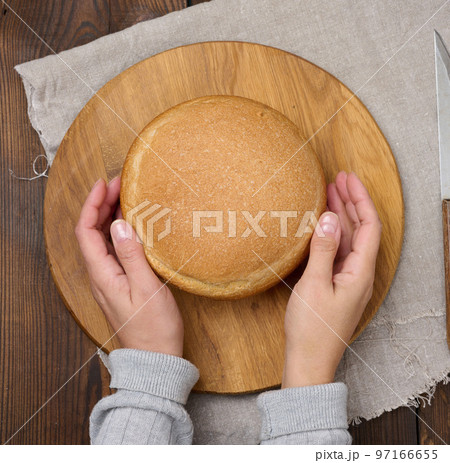 Round baked bread on a wooden board, brown table. View from above Round baked bread on a wooden board, brown table. View from above 97166655