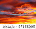 A setting sun colors the clouds in white, yellow, orange and purple, against the backdrop of a blue sky. A setting sun colors the clouds in white, yellow, orange and purple, against the backdrop of a blue sky. 97168005
