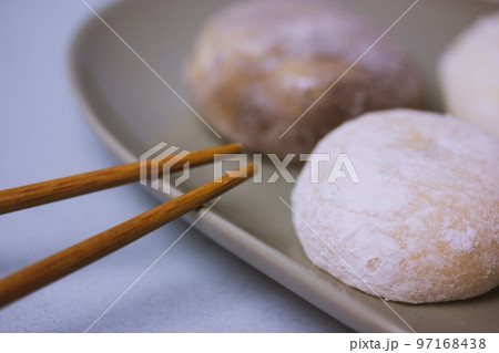 Chopsticks and traditional Japanese dessert mochi or daifuku in rice dough close-up. Four mochi ice cream balls on gray plate on blue-violet table selective focus. Asian sweet delicious food dessert. Chopsticks and traditional Japanese dessert mochi or daifuku in rice dough close-up. Four mochi ice cream balls on gray plate on blue-violet table selective focus. Asian sweet delicious food dessert. 97168438