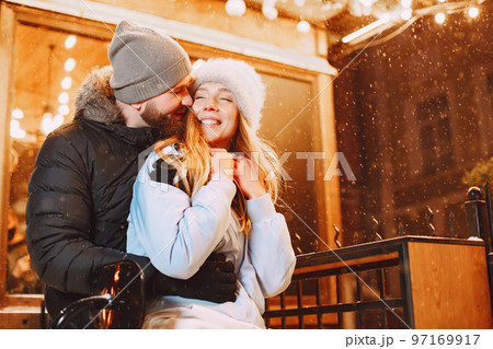 Winter holidays conception. Outdoor night portrait of young couple. Posing in street of European city. Winter holidays conception. Outdoor night portrait of young couple. Posing in street of European city. 97169917