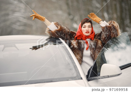 Attractive woman in wintertime outdoor. Lady with red lips. Famale by electro car. Attractive woman in wintertime outdoor. Lady with red lips. Famale by electro car. 97169958