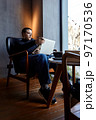 The woman looks at her laptop and makes notes in a notebook 97170536