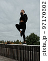 A woman in a black tracksuit does sports in the park 97170602