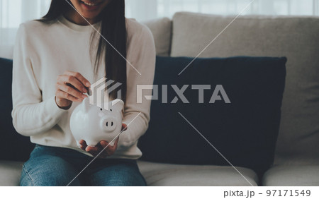 Asian woman putting coin in piggy bank. Save money and investment concept 97171549