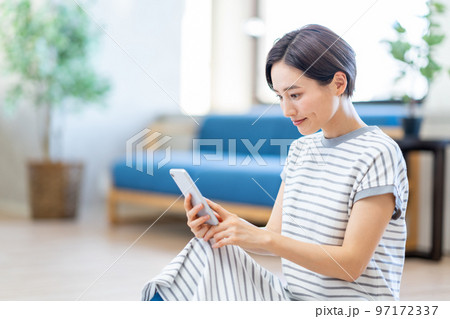 リビングでスマートフォンを操作する女性。 97172337
