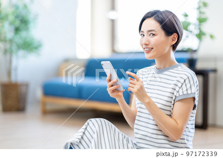 リビングでスマートフォンを操作する女性。 97172339