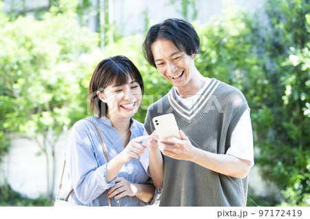 スマホで検索する若い夫婦 97172419