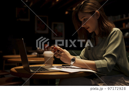 Young woman using smart phone and laptop at cafe. Young woman using smart phone and laptop at cafe. 97172928