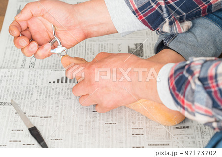 新聞紙の上で足の爪を切る男性 新聞紙の上で足の爪を切る男性 97173702