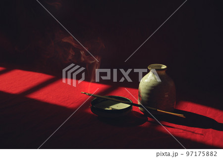 Smoke rising from an incense sticks in a porcelain platter hidden in the shadows showing the concept of meditation, mindfulness and mental wellbeing 97175882