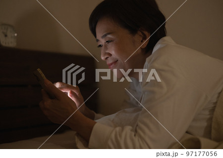 寝室で寝ながらスマホを見る日本人女性 97177056