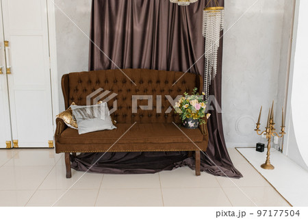 Luxury brown classic sofa with pillows and a bouquet of flowers in a vase in the living room of the house Luxury brown classic sofa with pillows and a bouquet of flowers in a vase in the living room of the house 97177504
