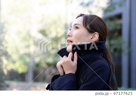 冬なので寒くてコートの襟をたてる女性 冬なので寒くてコートの襟をたてる女性 97177625