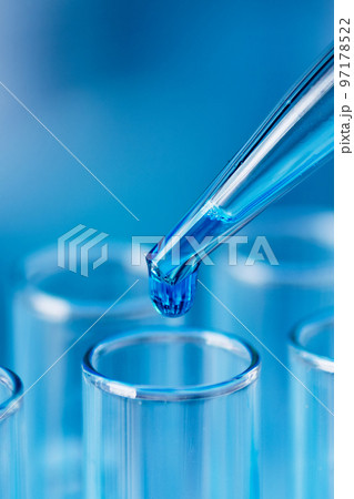 Test tubes with blue liquid water samples and pipette over blue background. Pipette dropping sample into test tube. Laboratory glassware, science laboratory research concept. 97178522