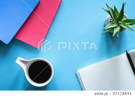 A cup of coffee and notepads on a blue background, minimalism. 97178643