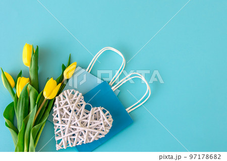 Flat lay blue background with flowers and paper bags. Flat lay blue background with flowers and paper bags. 97178682