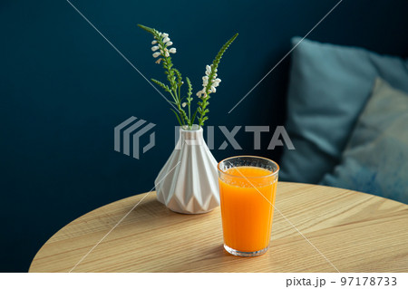 A glass of orange juice on a table in a blue...の写真素材