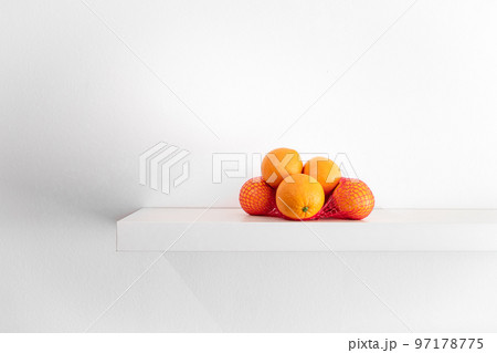 Fresh oranges in a grid on a shelf on a white background. Fresh oranges in a grid on a shelf on a white background. 97178775