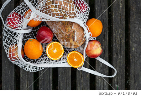 Fruits and bread in a shopping bag on a wooden background. 97178793