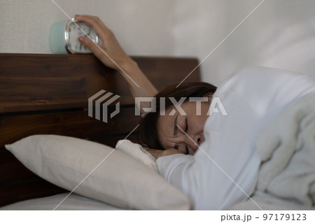 寝起きが悪い・目覚まし時計を止める女性 97179123