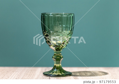 Glass green textured goblet on a blue background. 97179553