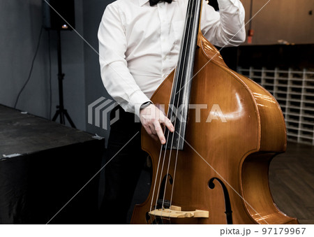 musician in a white shirt plays the double bass 97179967