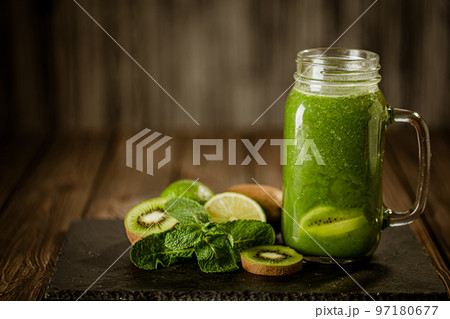Front view of green smoothie in glass jar and ingredients on wooden background. Good food concept Front view of green smoothie in glass jar and ingredients on wooden background. Good food concept 97180677