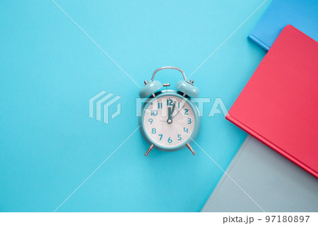 Alarm clock and notepads on a blue background, flat lay. Alarm clock and notepads on a blue background, flat lay. 97180897