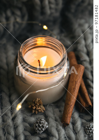 Close-up, candle and cinnamon sticks on the background of a gray knitted element. 97181482