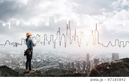 Female engineer in hard hat with blueprint 97183842