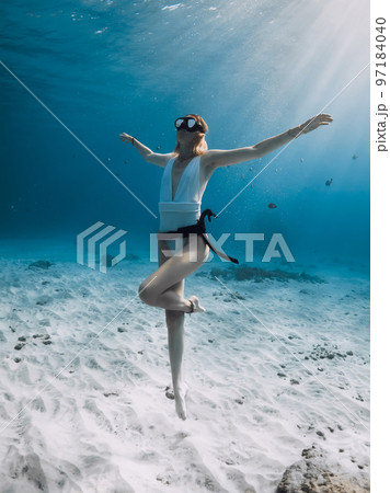 Attractive freediver posing underwater. Freediving with woman in blue ocean with amazing sun rays 97184040